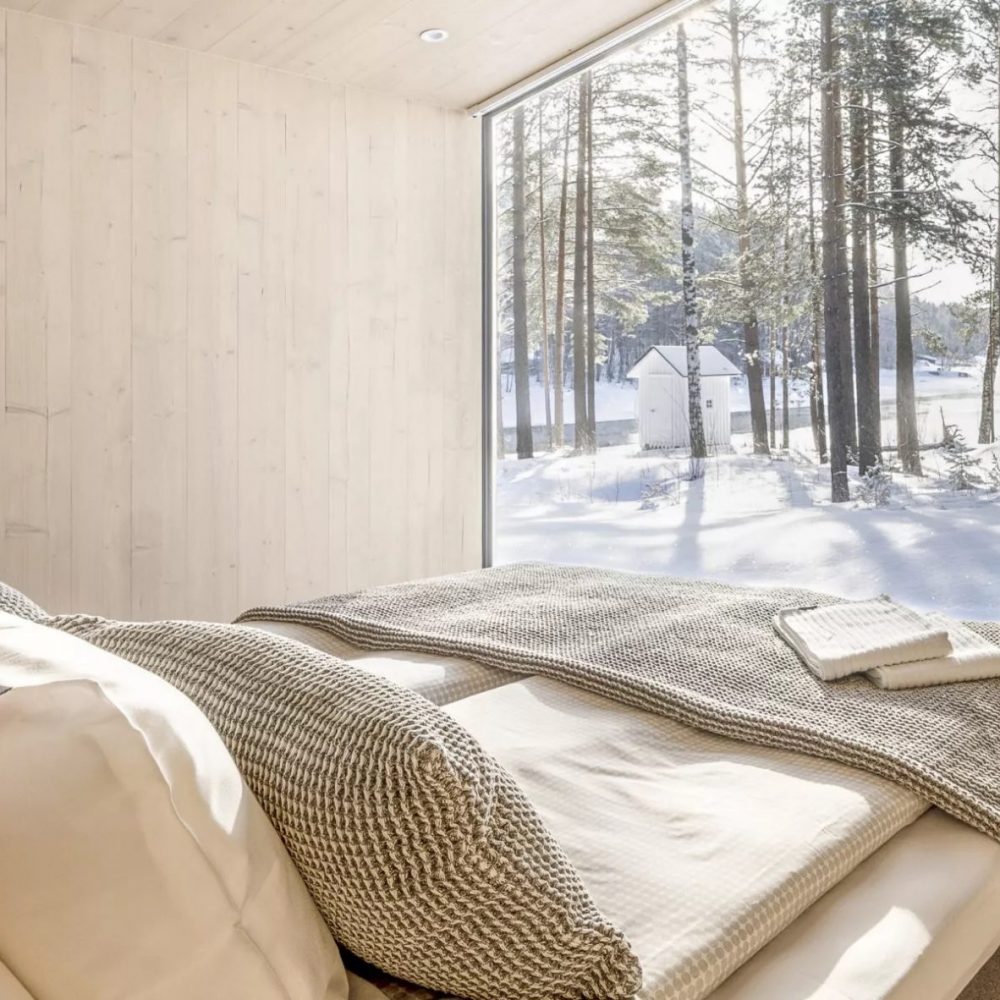 Oravin Kanava Resortin makuuhuone, jossa suuri ikkuna talviseen metsään