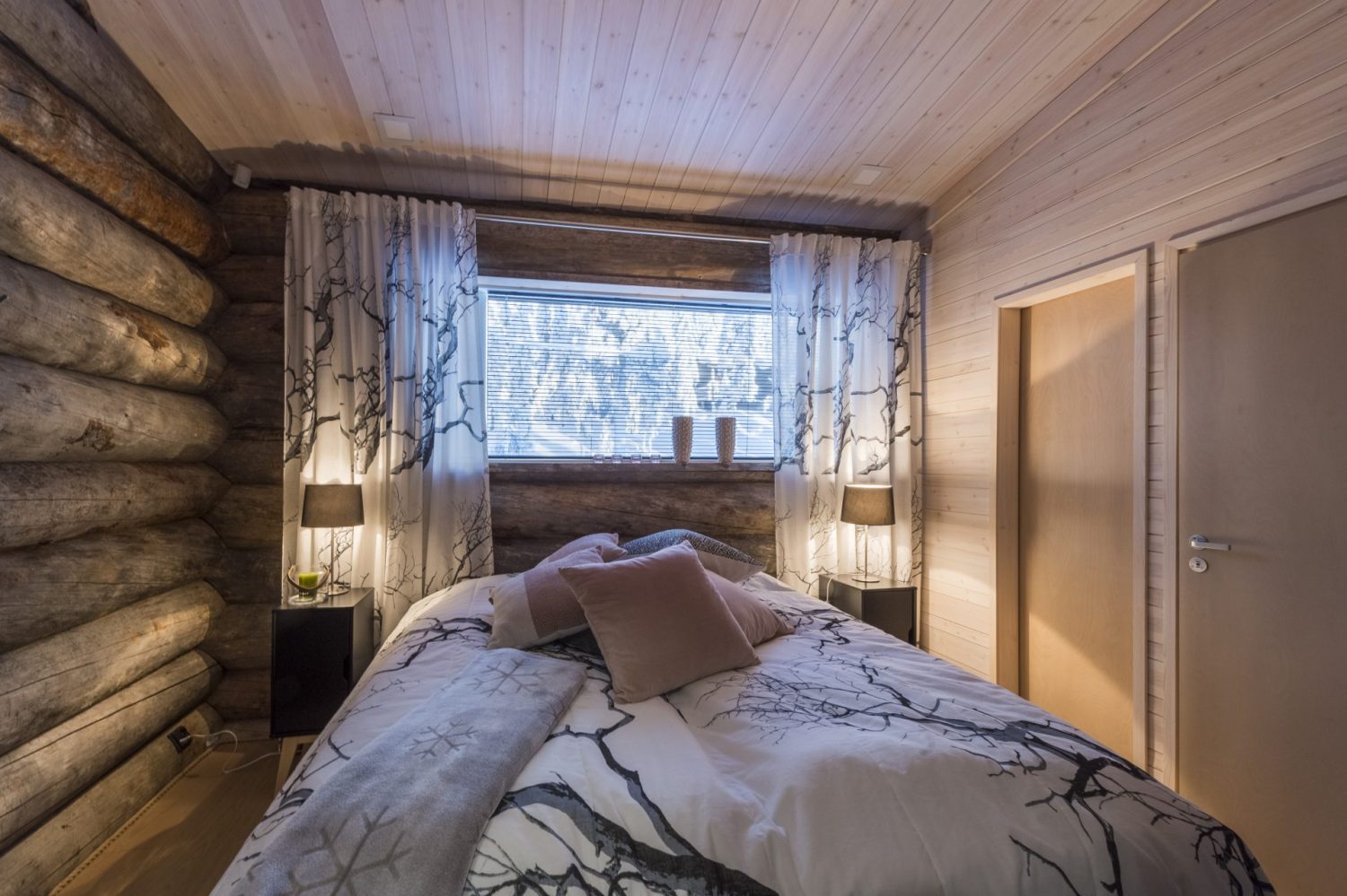 Makuuhuone, jossa kuviollinen päiväpeite ja ikkuna metsään