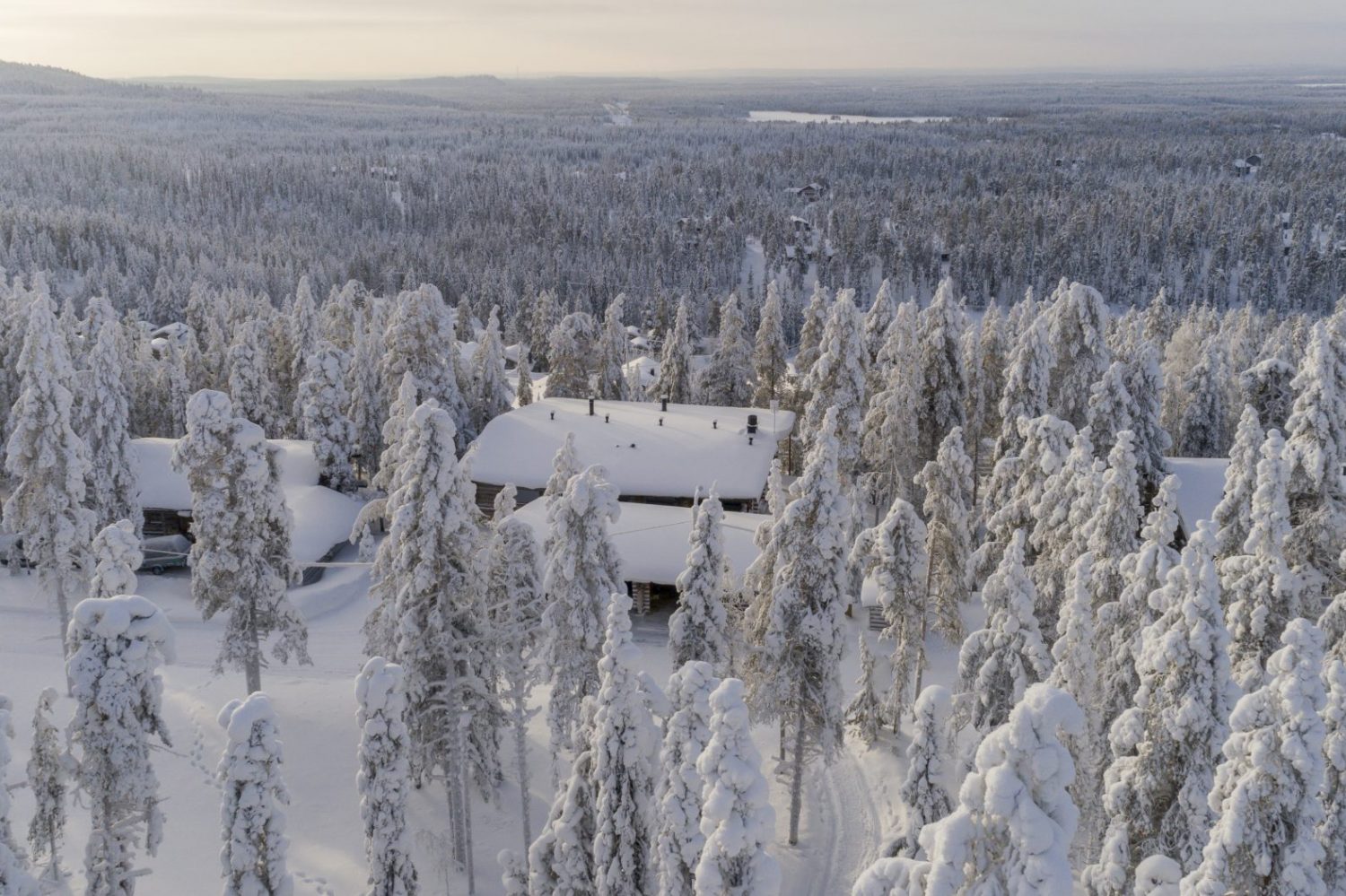 Näkymä ylhäältä: huvilan katto tykkymetsän keskellä ja laaja tunturimaisema