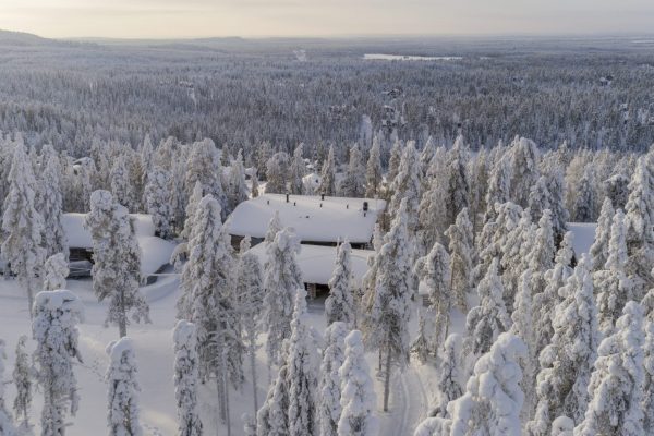 Näkymä ylhäältä: huvilan katto tykkymetsän keskellä ja laaja tunturimaisema